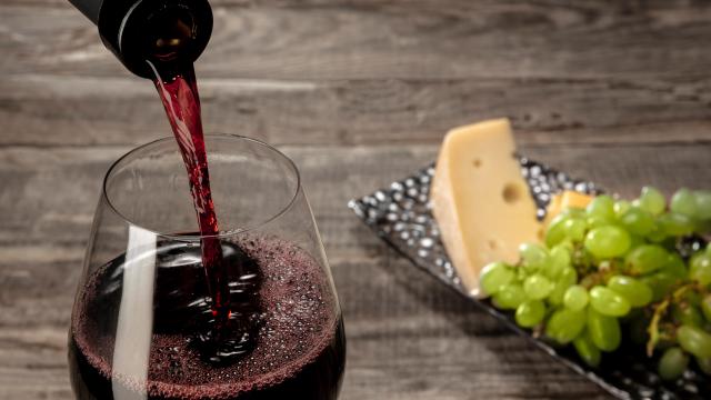 Bottle And Glass Of Red Wine With Fruits Over Wooden Table Min