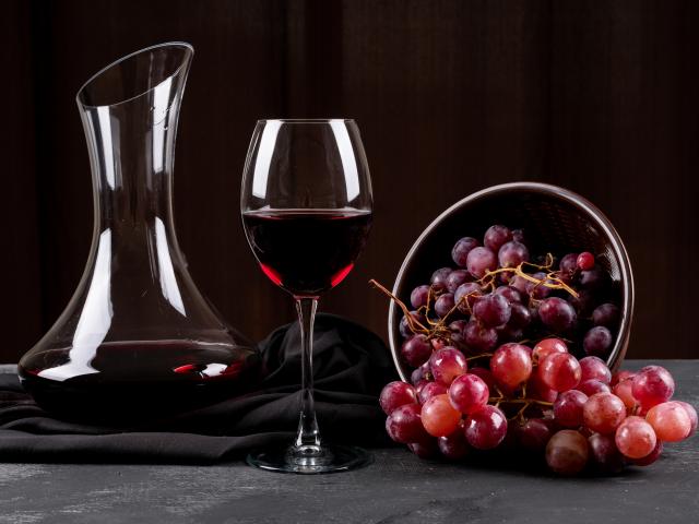 side-view-of-jug-with-red-wine-and-grape-on-dark-horizontal.jpg